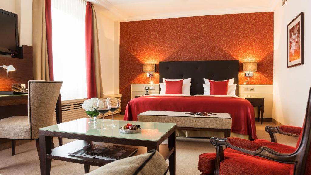 Habitación de hotel con cama con colcha roja en Althoff Hotel am Schlossgarten, en Stuttgart