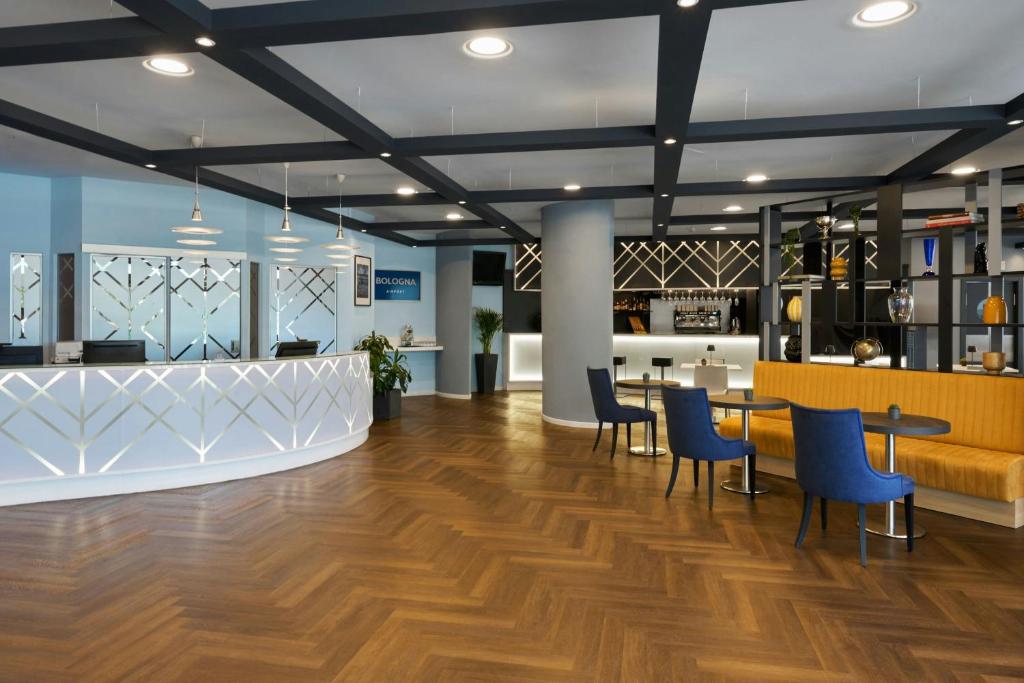 an office lobby with wooden floors and blue chairs at Four Points Flex by Sheraton Bologna Airport in Bologna