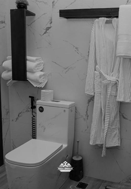 a bathroom with a toilet and towels on a wall at Geza Breeze Residence in Dar es Salaam