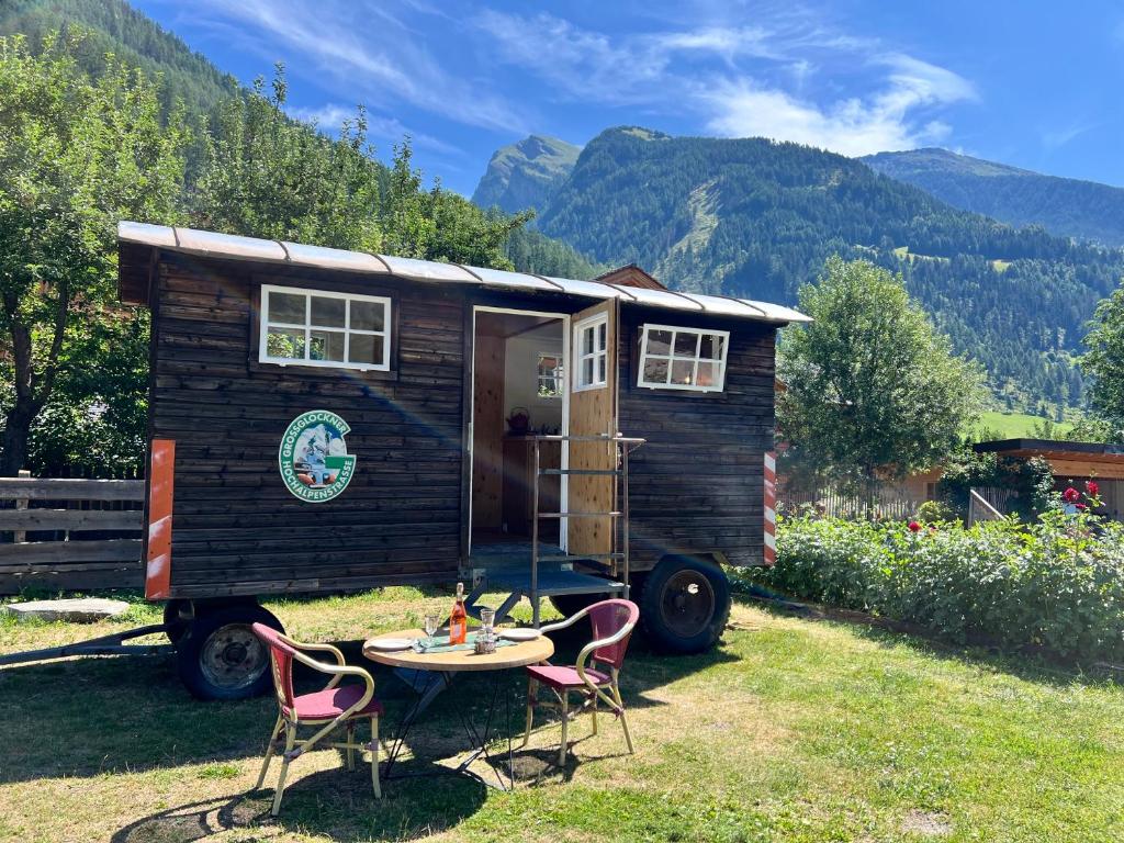 a tiny house on wheels with a table and chairs at Schlosswirts Wohnmobilstellplatz, Schäferwagen und Bauwagen Großglockner Hochalpenstrasse in Döllach