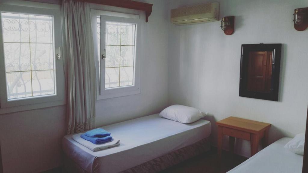 ボドルム・シティにあるMavi Apart Otelの小さなベッドルーム(ベッド2台、窓2つ付)が備わります。