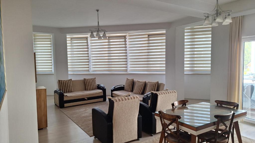 a living room with a table and chairs and windows at Orges Apartament in Struga