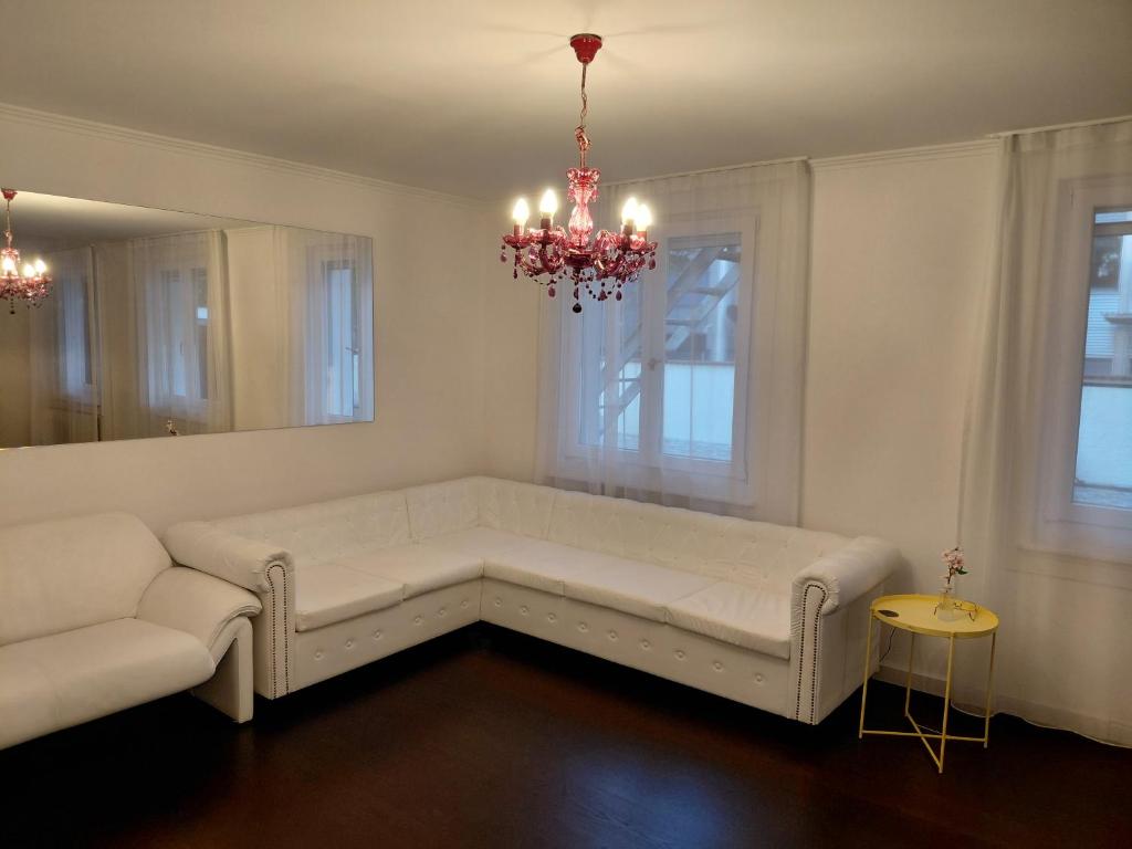 a living room with a white couch and a chandelier at Berner Hostel in Bern
