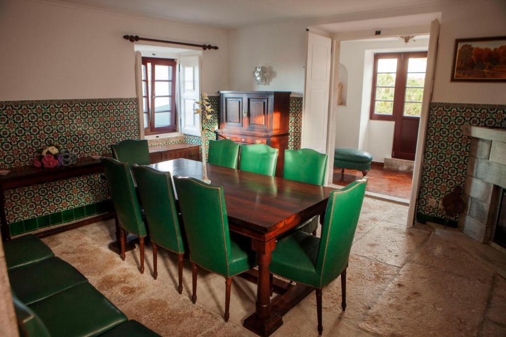 a dining room with a wooden table and green chairs at Quinta Santo António in Sintra