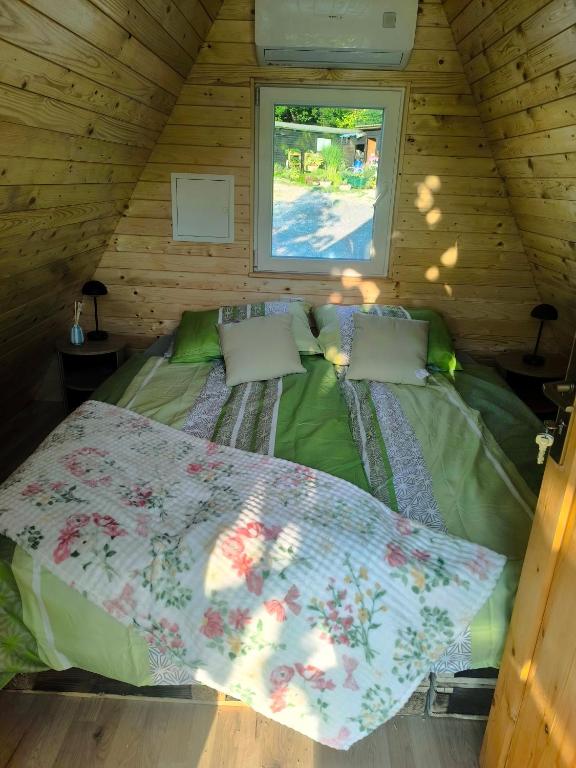 a bed in a wooden cabin with a window at Hiška Timi in Malečnik