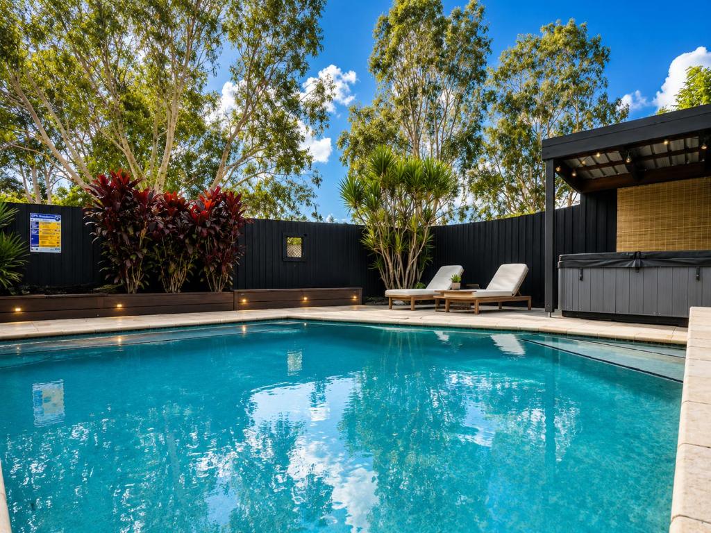 a swimming pool in a backyard with a black fence at Peaceful tropical retreat with pool, mineral spa & Games room in Gold Coast