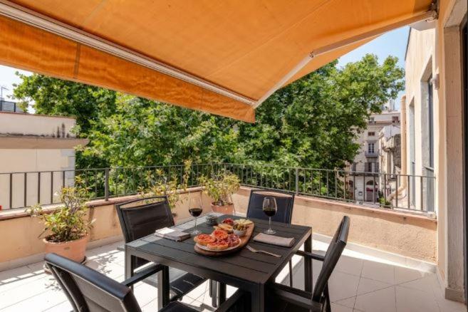 a table with a plate of food and wine glasses on a balcony at Apartament La Placeta Figueres in Figueres