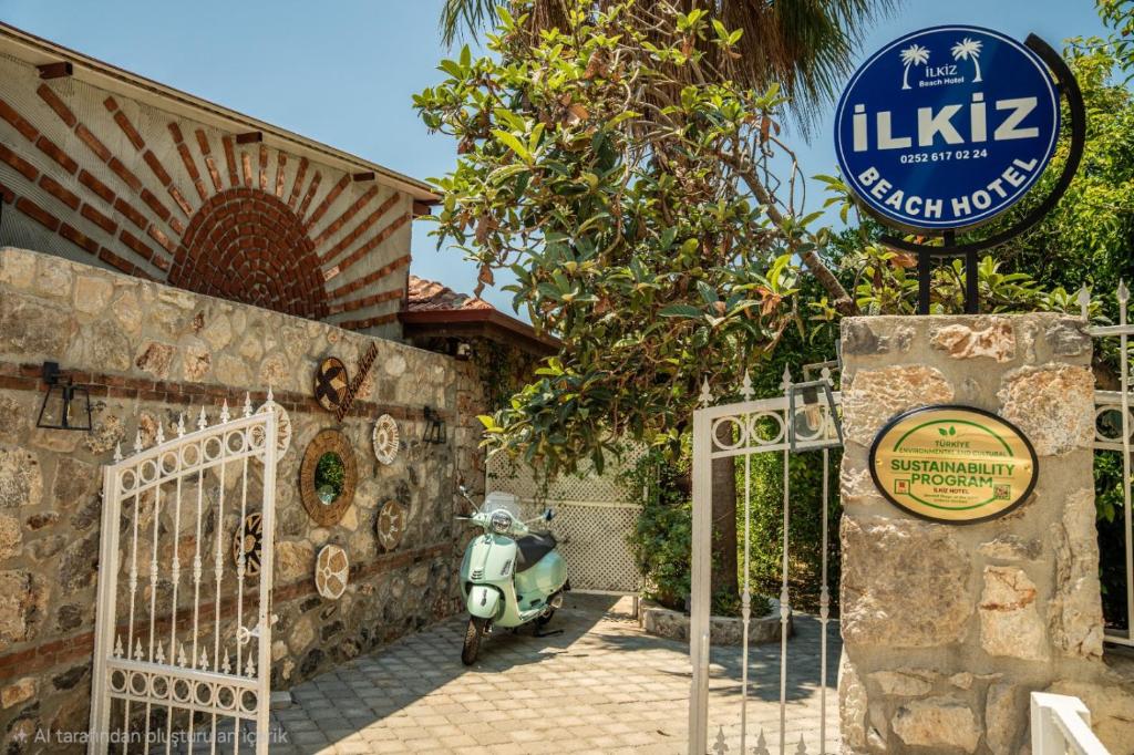 a scooter parked in front of a house with a sign at İlkiz Beach Hotel in Oludeniz