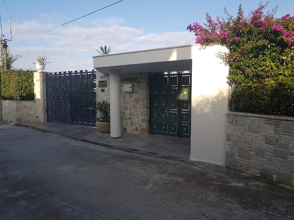 a building with a garage with a fence and flowers at Μαγευτική βίλα Κωνσταντίνα in Nerántza