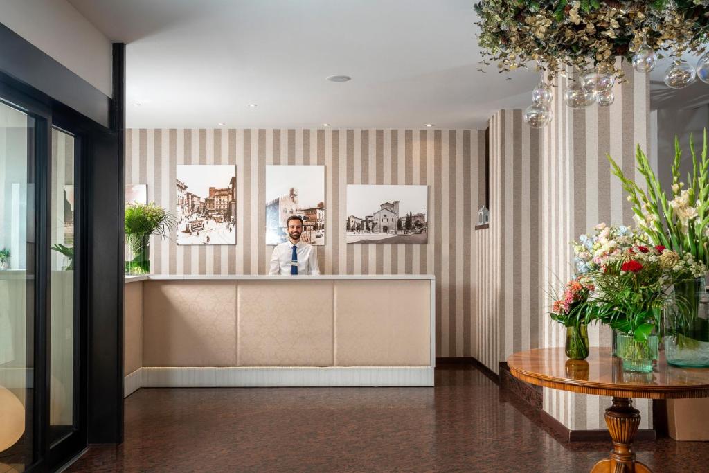 a man standing behind a counter in a lobby at Re Enzo in Bologna