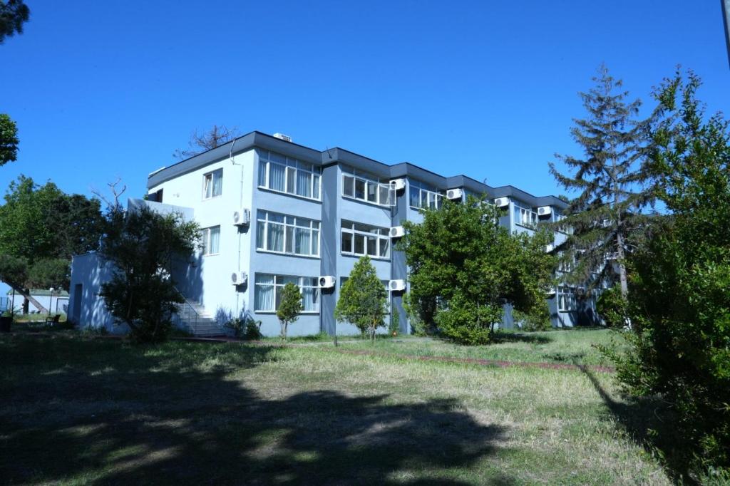 a large white building with trees in front of it at Karev Sport Hotel in Gümüşyaka