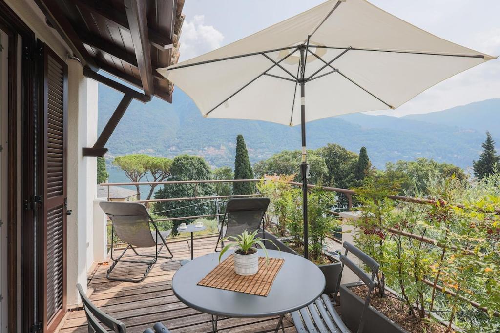 a table and chairs on a balcony with an umbrella at The Como Pet Nest in Laglio