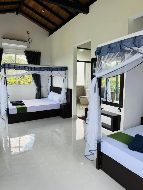 a bedroom with two beds and a mirror at Rainforest mountain resort in Deniyaya