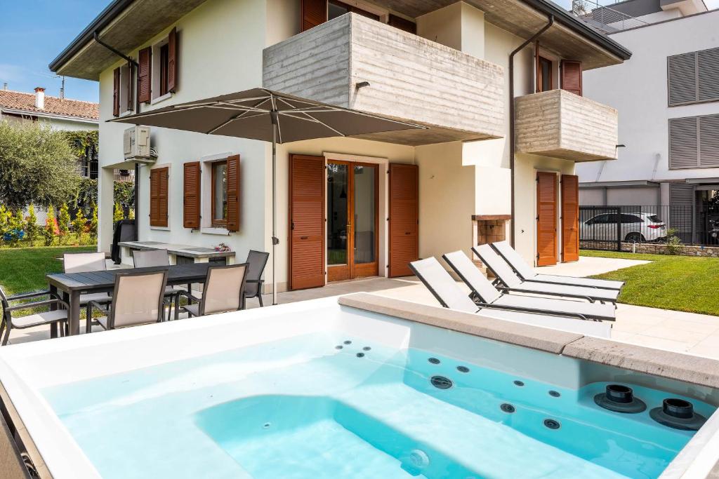 a pool with chairs and an umbrella in a backyard at Villa Sonia in Bardolino