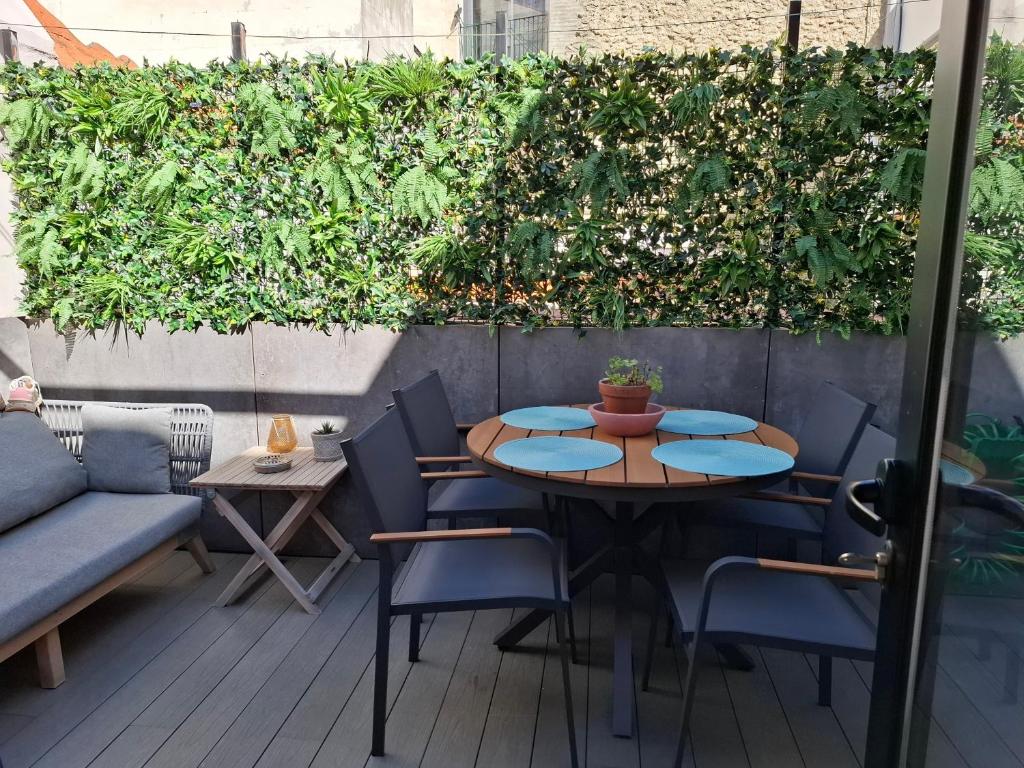 a patio with a table and chairs and a green hedge at Dulce y acogedor in Vilanova i la Geltrú