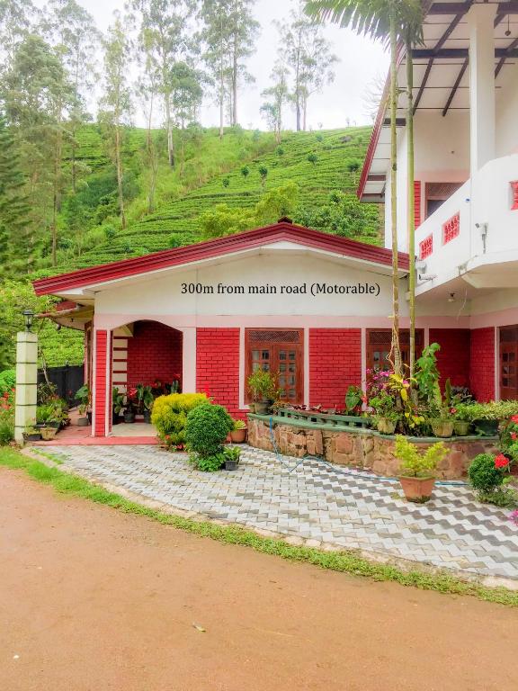 a red building with a mountain in the background at Madhusha Rest in Maskeliya
