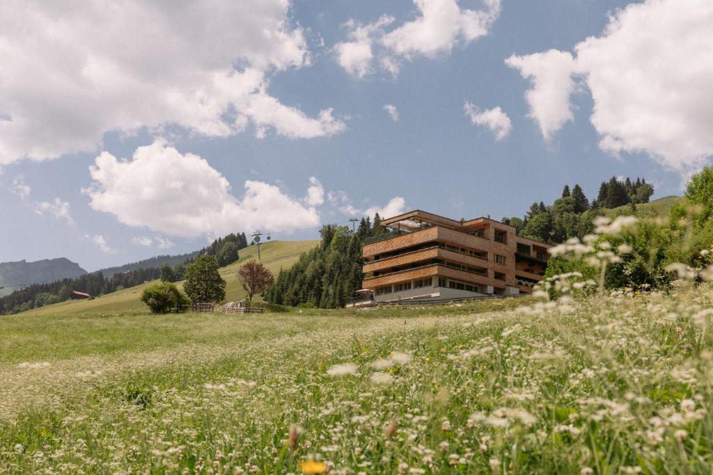 a building on a hill with a field of flowers at Hotel Marten -Joker Card Partner- in Saalbach-Hinterglemm