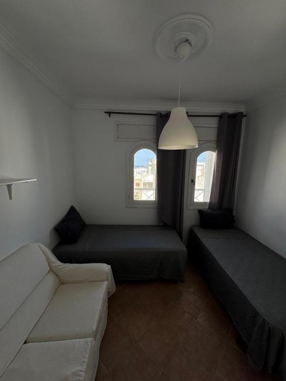 a small room with two beds and a couch at Appartement à Miramar in Martil