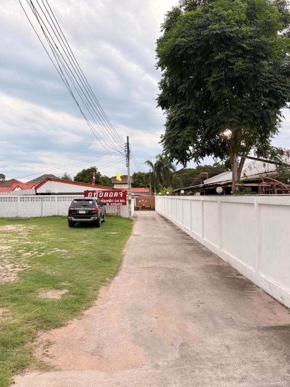 a car parked in a yard next to a white fence at ฤทัยลอดจ์ in Ban Tao Than