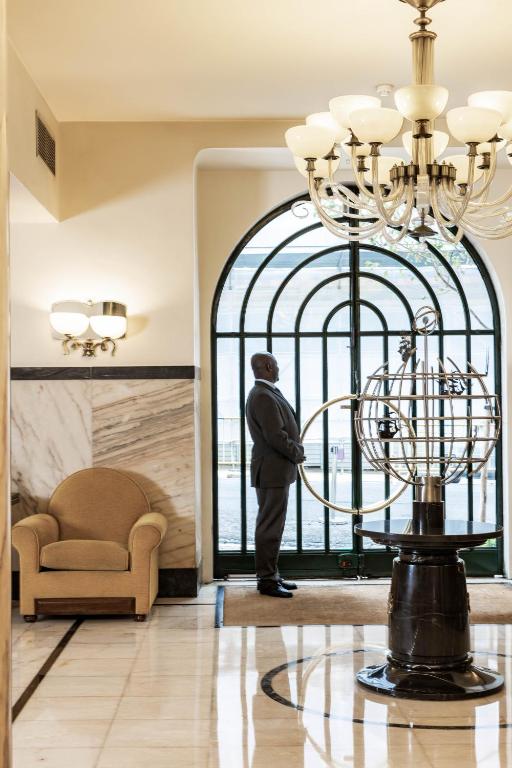 a man standing in a room looking out of a gate at Hotel Britania Art Deco Lisboa in Lisbon