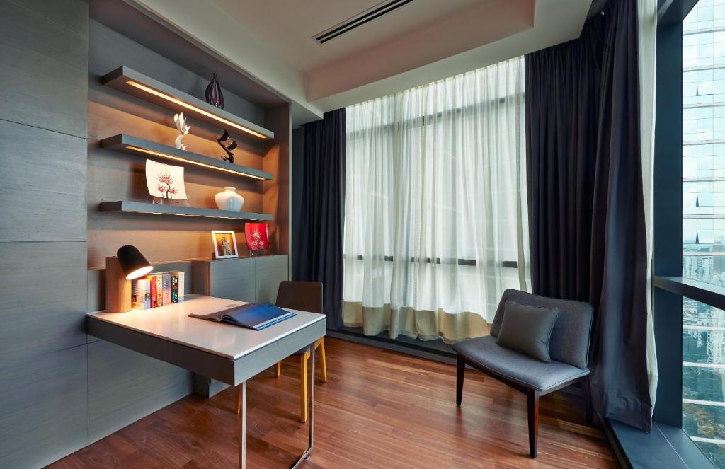 A built-in writing desk beside a curtained window and a separate lounge chair.