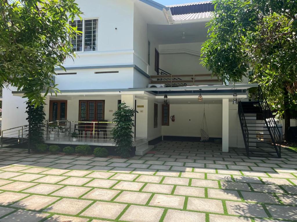 a white house with a patio in front of it at Bright Nest Service Villa Munroe in Kollam
