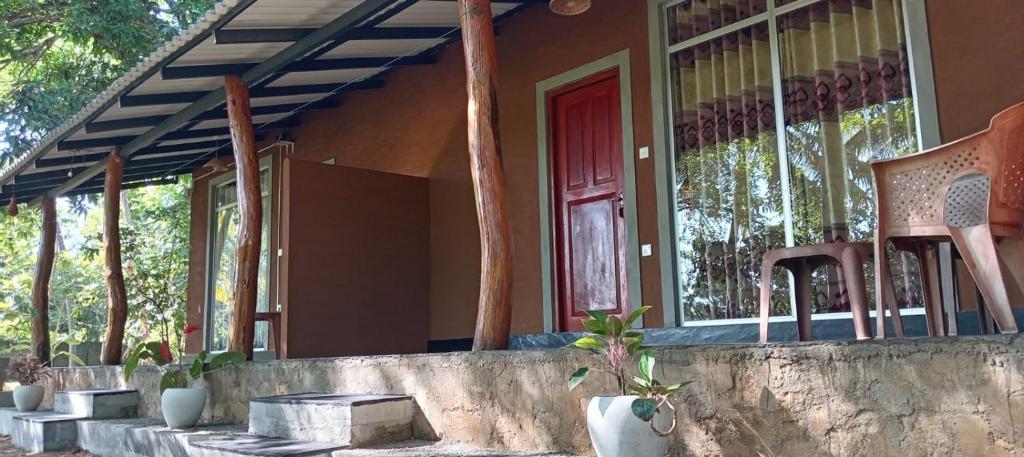 a house with a red door and some chairs at Peacock Lake Villa in Habarana