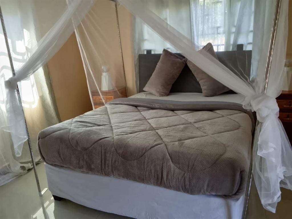 a bedroom with a bed with a canopy at Dewclaw Baobab Safari Lodge in Mfuwe