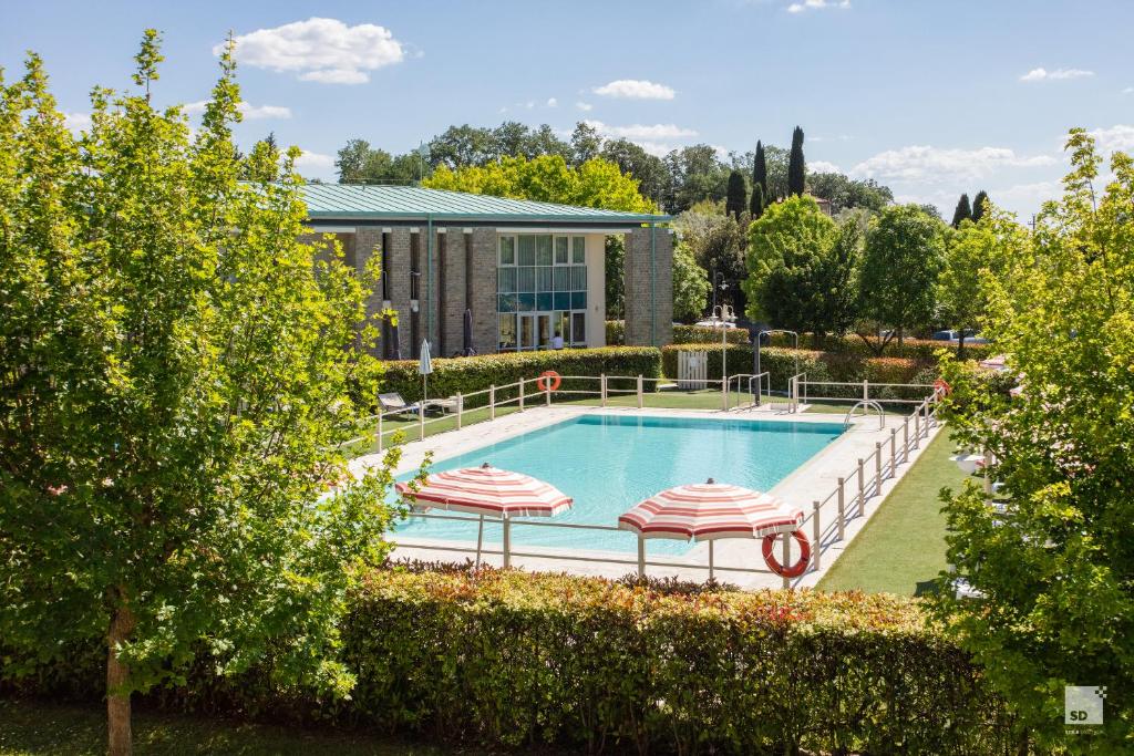 a swimming pool with two umbrellas and a building at Chianti Village - Free Parking & Pool in Tavarnelle Val di Pesa
