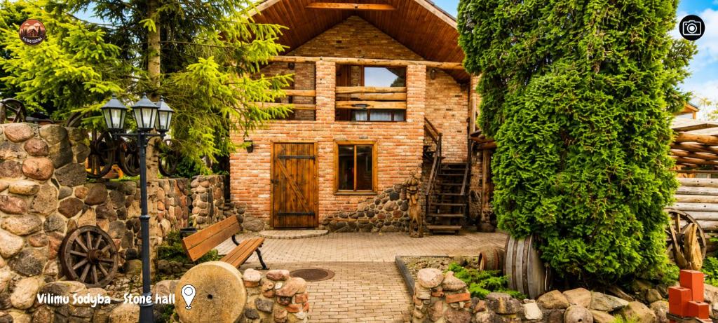 a brick house with a wooden door in a yard at Vilimu Sodyba - Stone Hall in Kriukai