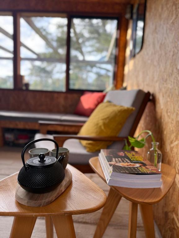 a room with two tables with a tea pot and a book at The Grasshouse Cabins in Burrawang