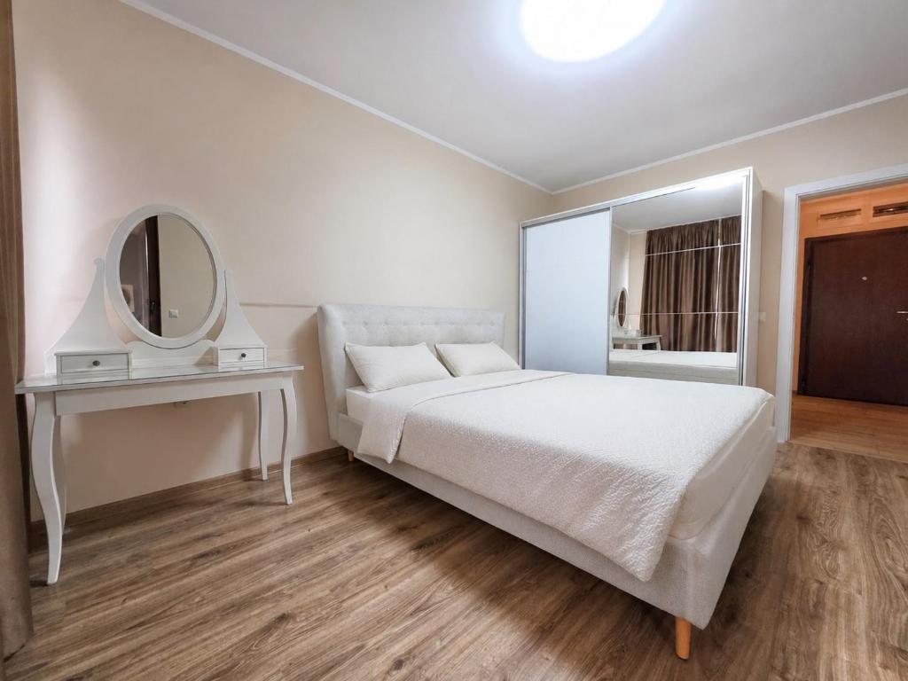 a white bedroom with a bed and a mirror at Mountain View Apartment in Sofia