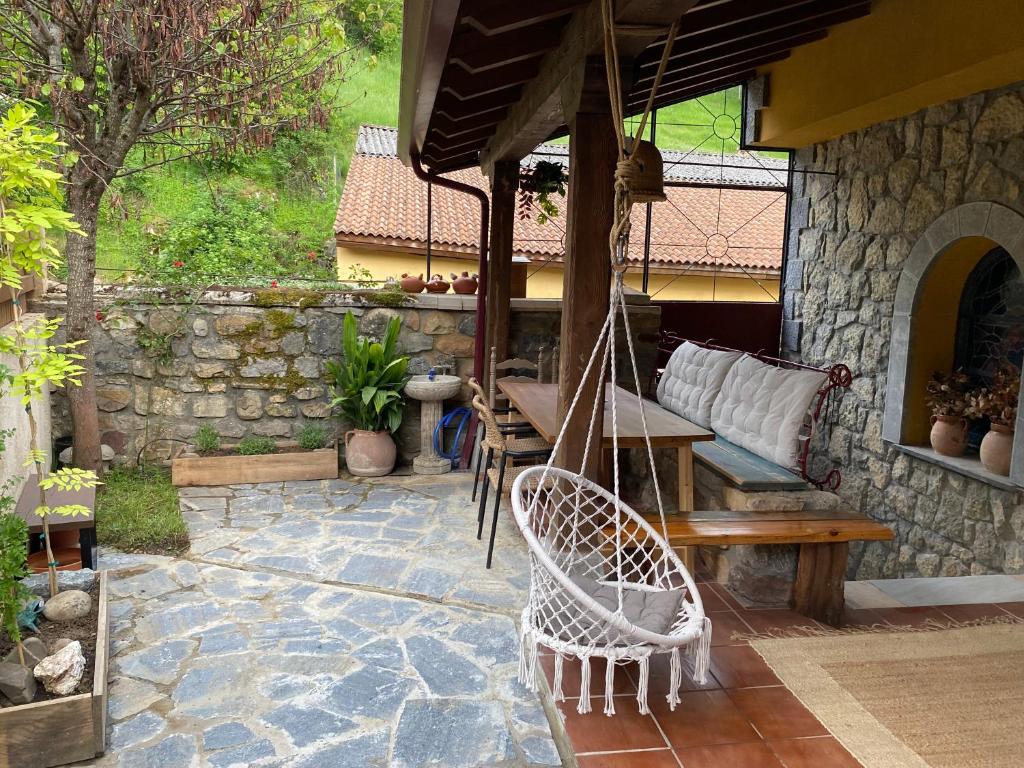 a patio with a swing and a table and a stone wall at Legendarium Casa Rural in Salamón