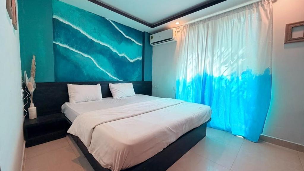 a bedroom with a large bed with a blue wall at Hotel Simba by Hakuna in Arambol
