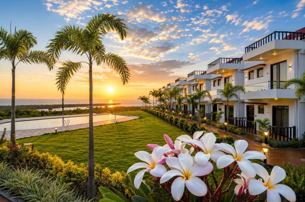 a row of houses with palm trees and a sunset at Baywatch Resort Bhogave Beach in Vengurla