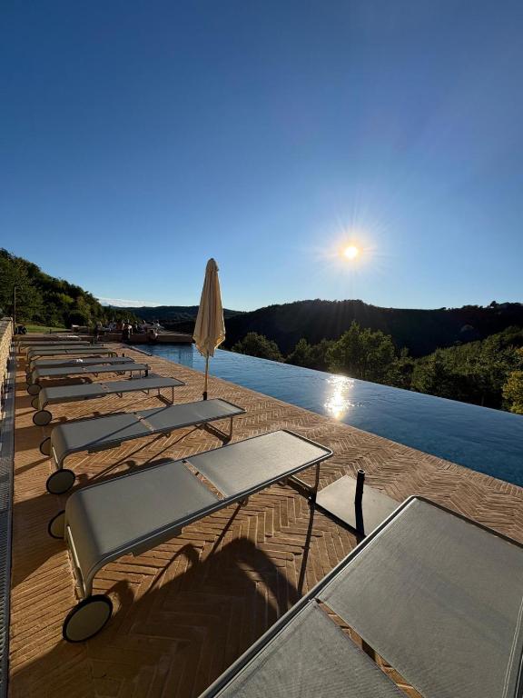 a row of tables and umbrellas next to the water at Borgo Isolabella - Wine & Vermouth Relais in Loazzolo