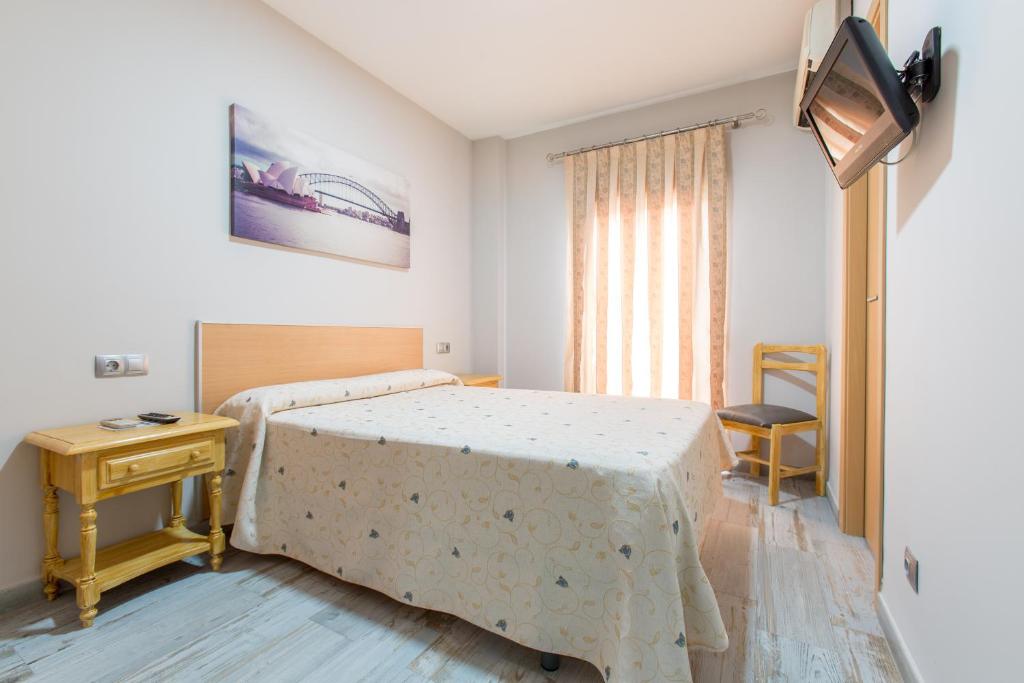 Schlafzimmer mit einem Bett, einem Tisch und einem Fenster in der Unterkunft Olympia Ronda Hostel in El Puig