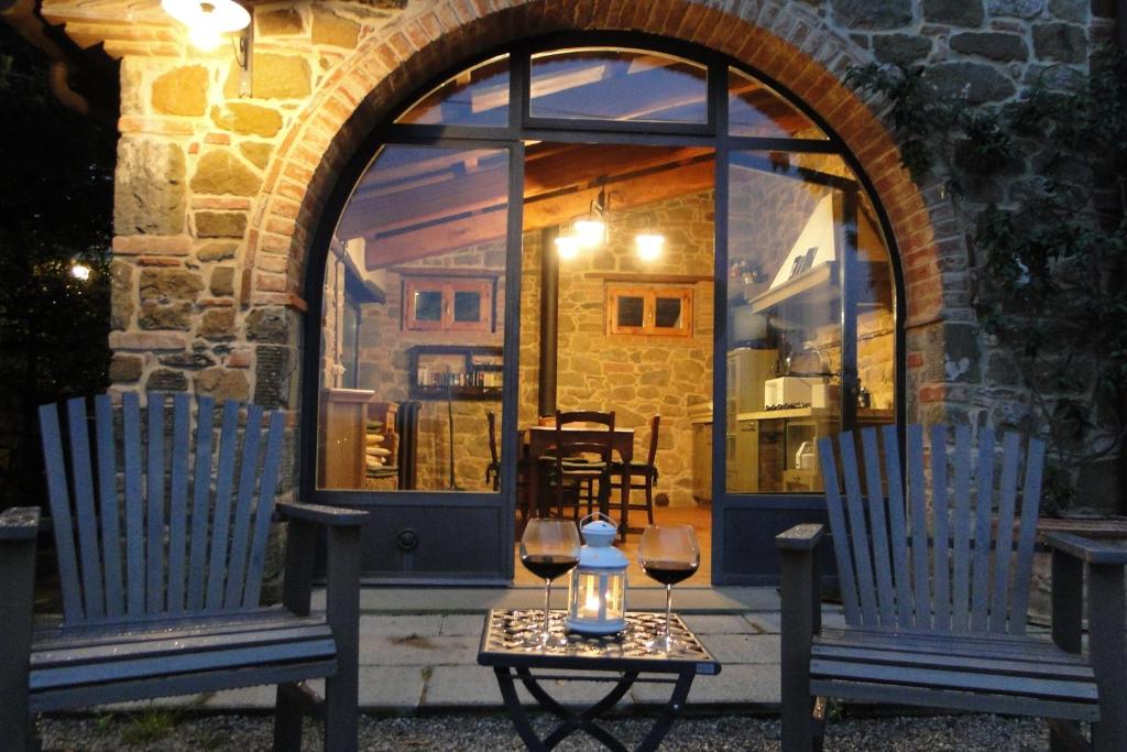 2 Stühle und ein Tisch mit Weingläsern vor dem Fenster in der Unterkunft Villa Ceppeto in Monte San Savino