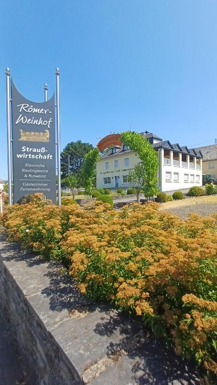 a sign in front of a building with flowers at Ferienwohnung Römerweinhof in Neumagen-Dhron