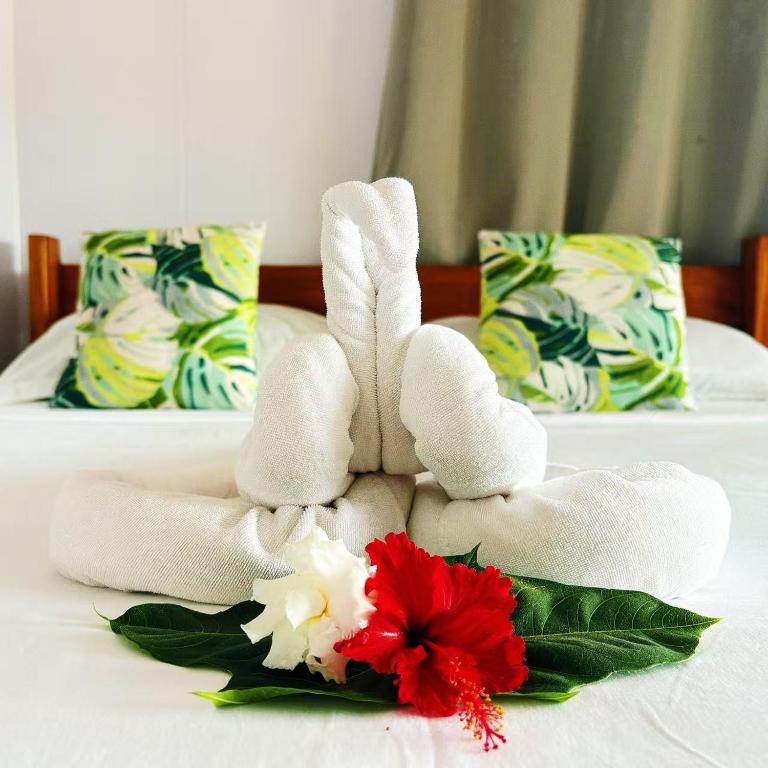 a white towel bunny sitting on a bed with flowers at Room With A View & Apartment Style in Port Vila