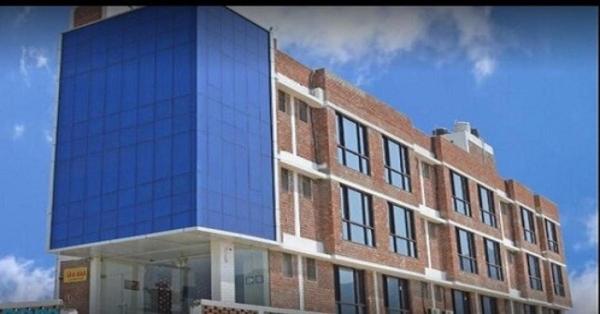 a large brick building with a blue glass at Hotel Tanman Continental, Rajgir in Rājgīr Kund