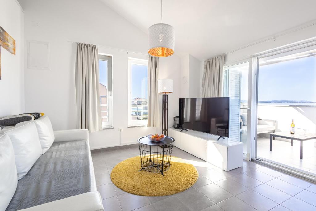 a white living room with a television and a table at Apartments 2A in Petrcane