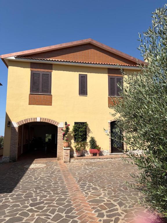 a large yellow building with a stone driveway at B&B Residenza Gigina in Sezze