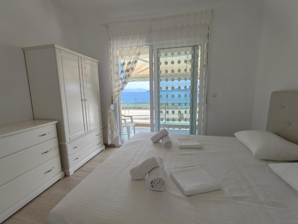 a white bedroom with a bed with towels on it at Апартаменты Елена in Nea Peramos