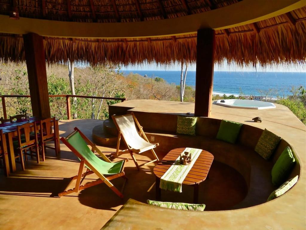 a room with a table and chairs and a view of the ocean at Casa Monte Pacífico, jacuzzi, wifi Starlink y vista al mar in San Agustinillo