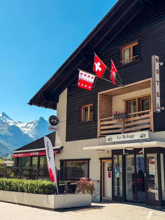 a building with canadian flags in front of it at Le Refuge Hotel Restaurant in Ayer