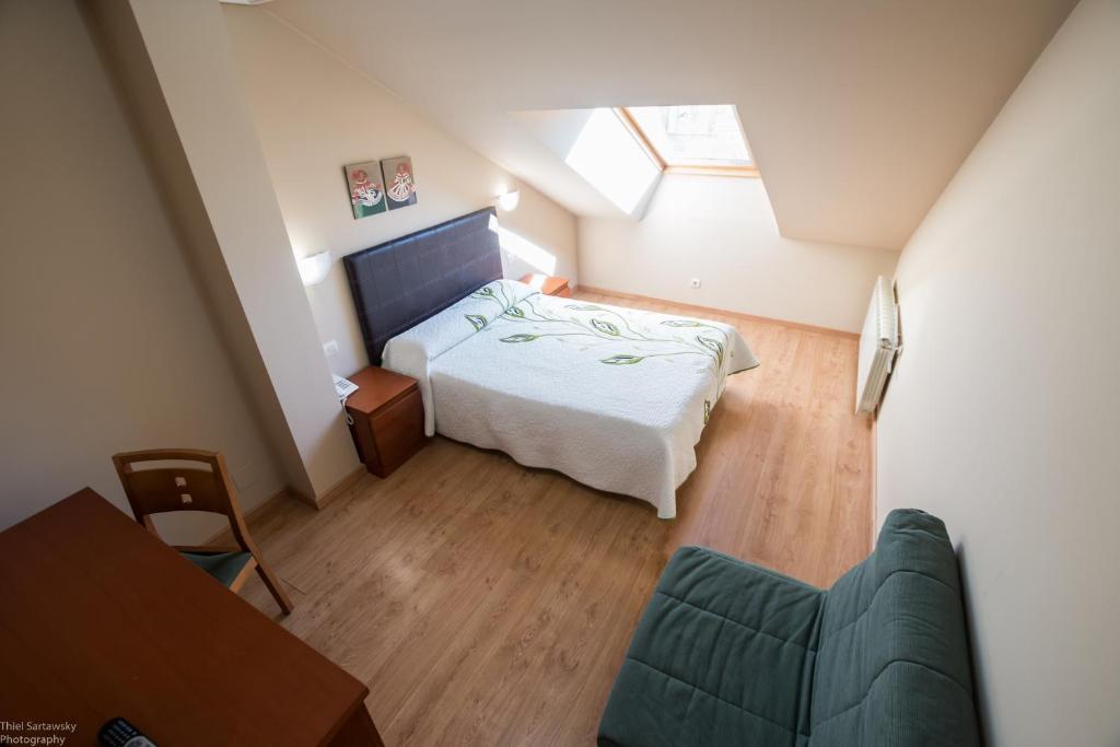 a small bedroom with a bed and a couch at Hotel El Roble in Cervera de Pisuerga