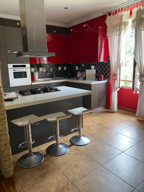 a kitchen with red cabinets and two bar stools at Casa Vacanza Pigna in Pigna
