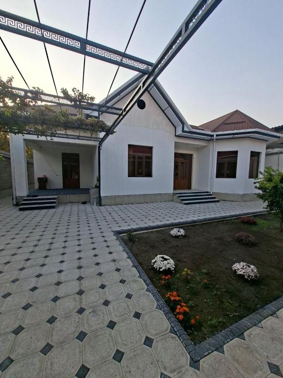 a white house with a patio and a garden at Mamura Karimova in Andizhan