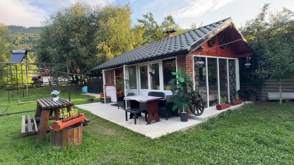 a small house with a table in a yard at Casuta -Dor de Munte -Ceahlau in Bistricioara